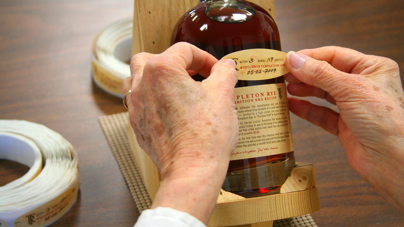 A bottle of Templeton Rye is labelled by hand.